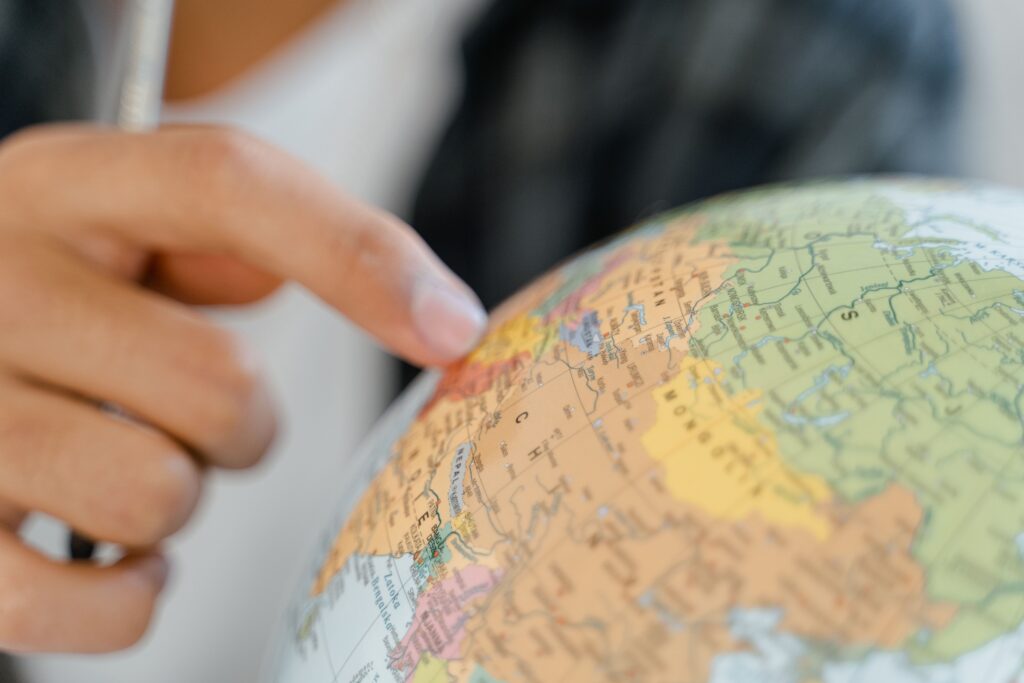 A close-up of a hand pointing at a globe, highlighting exploration and travel concepts. Earth Is Round—Maps Are Flat