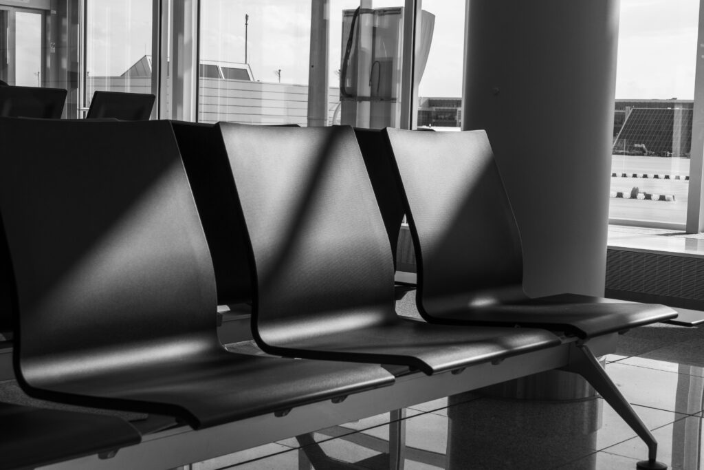 black and white photo showcasing empty chairs in an airport terminal.